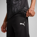 A person is wearing black Puma Team CUP 25 training pants, with the Puma logo visible on the leg.